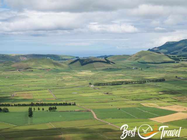 Zoom photo of several grass covered volcanic craters in the distance.