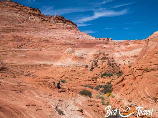 A hiker in front of four sandstone buttes in orange and reddish clolour.