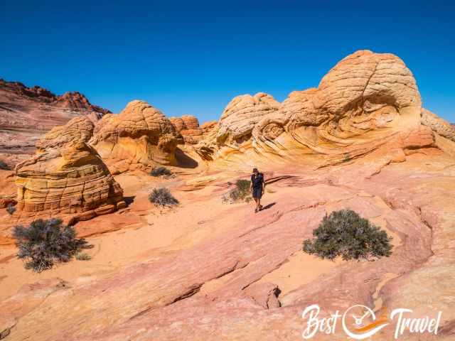 A hiker between pastel coloured rock formations.
