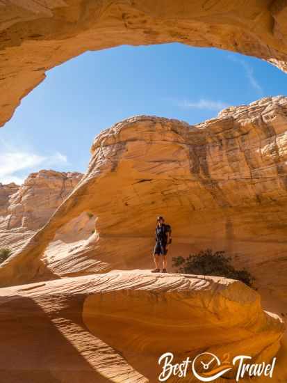 A hiker on a rock with Melody Arch in the back.