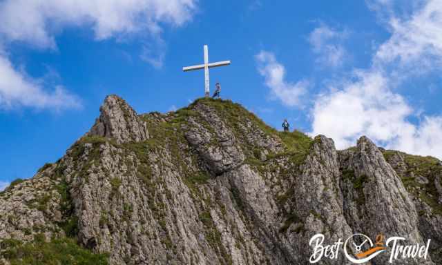 Two hikers at the cross on the peak of Brandnerschrofen