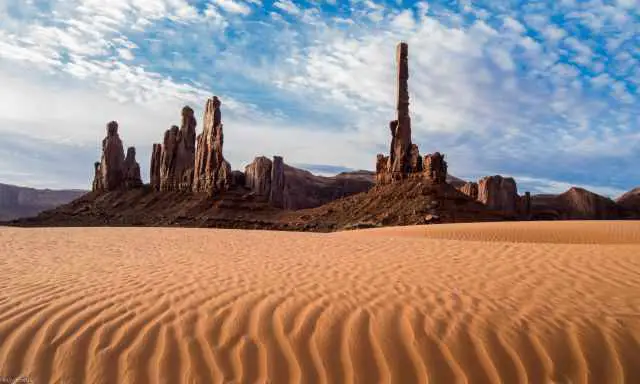 The Totem Pole and the desert red sand with a blue sky