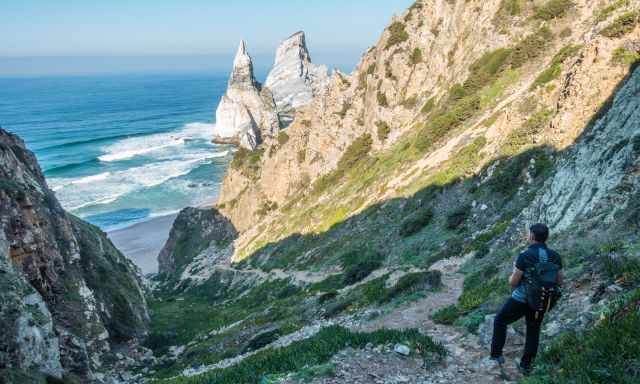 Man on trail looking down to Ursa Beach