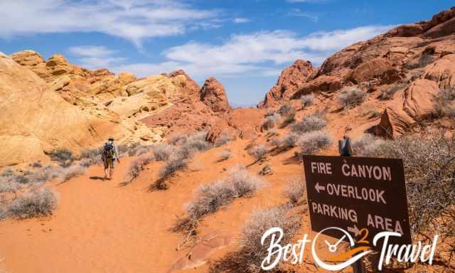 A man hiking through red sand and red sandstone formations