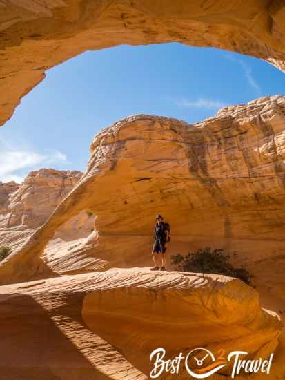 A hiker on a rock surrounded by sand.