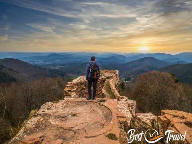 A hiker on the top of the ruins watching the sunrise