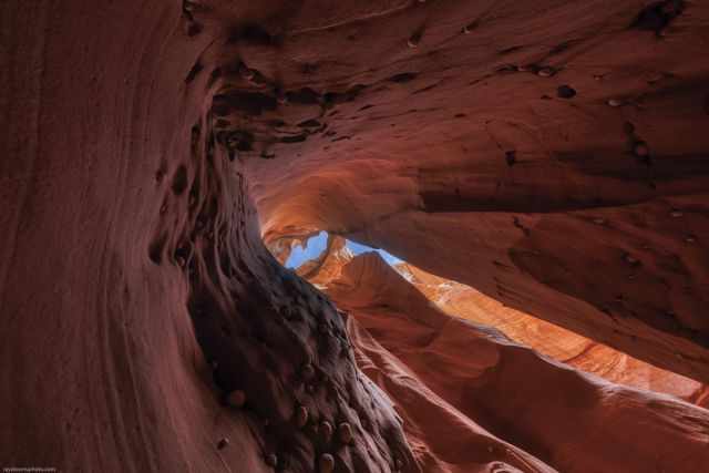 The view up out of the slot canyon to the sky with pebbles at the wall